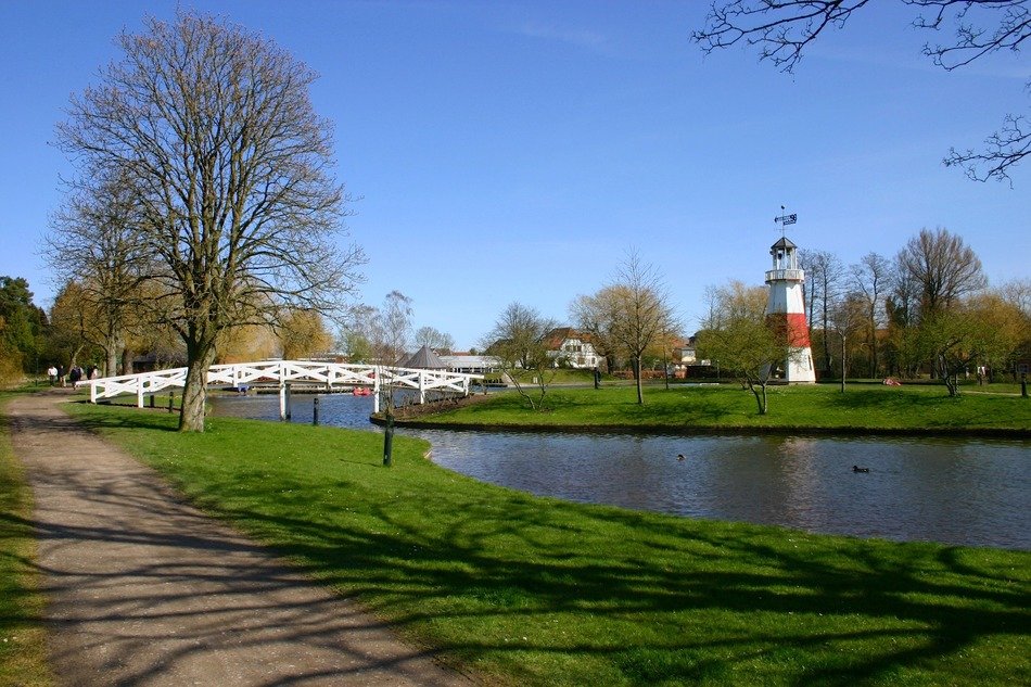white wooden bridge across chanel in park at spring, denmark, kolding