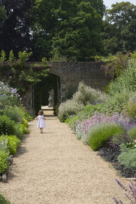 child walks on path in nymans garden at summer, uk, england, sussex