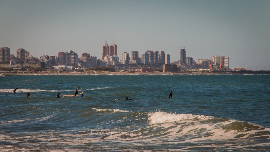 people resting in sea surf at scenic modern city, argentina, mar del plata