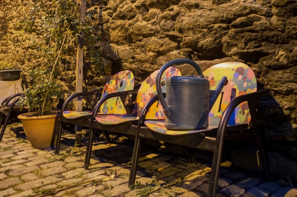 watering can on colorful chairs on the street near the wall
