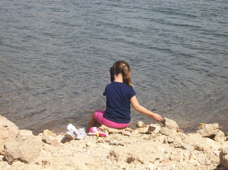 child on stones near the water