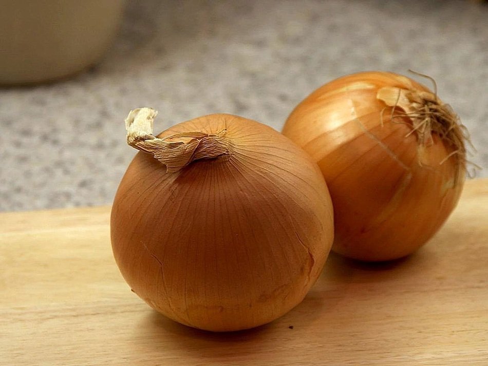 two yellow and brown onions on the wood