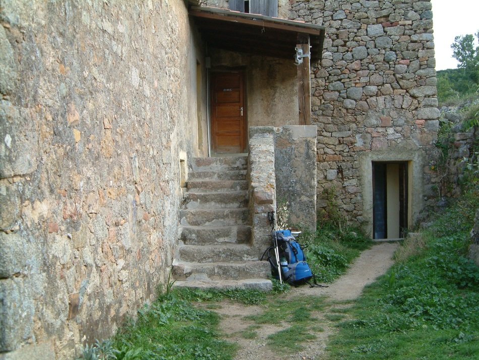 blue backpack near a stone house in the mountains