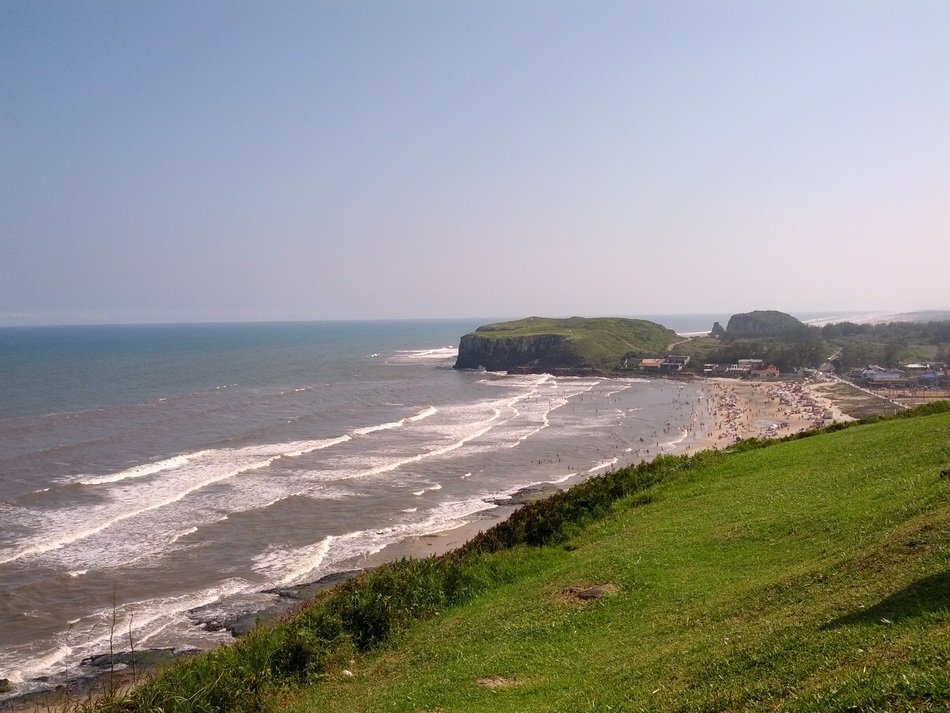ocean waves near the green hill