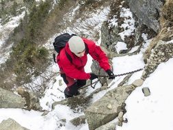 climber in a red jacket climbs the Alpine mountain