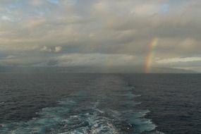 rainbow between clouds above sea