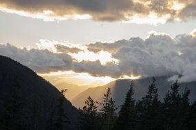 sun behind the clouds over the mountains
