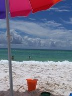 beach umbrella in an orange bucket by the sea