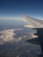 plane wing above alpine mountains