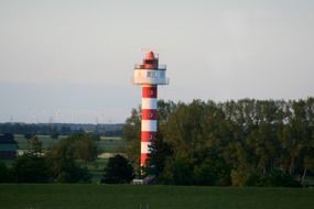 landscape of lighthouse on the shore near green trees