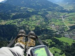 paragliding, legs of person with gps altimeter above scenic summer countryside