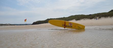 yellow surf board at water, uk, cornwall, porthkidney beach