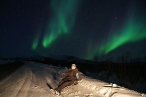 man on the mountain during the northern lights