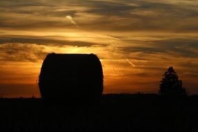 black silhouette of a straw bale at sunset