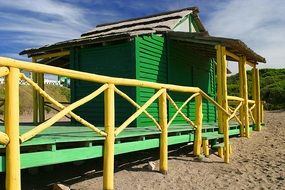 Green cabin on a sand beach