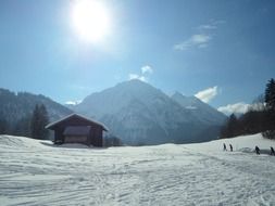 bright sun over a hut in the snowy alps, allgau