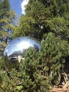 large mirror ball on a background of green trees on a sunny day