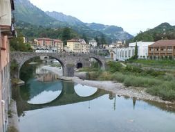 reflection of a stone bridge in a river in Italy