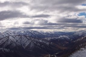 snowy mountains beneath grey clouds, new zealand, queenstown