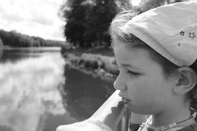 black white photo of a girl on a bridge across the lake