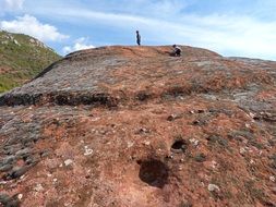 people on top of red sandstone on beautiful landscape at blue sky background with white clouds