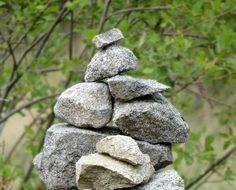 stacked gray stones on a background of green bush