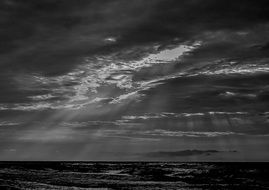 Black and white photo of the beautiful waterscape with light among the clouds