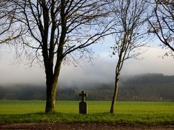 headstone with a cross on a green field