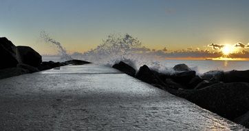 sunset on the background of the spray of waves on the waterfront