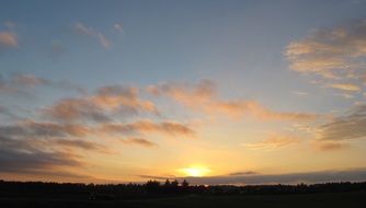sun beyond the horizon with clouds in the sky