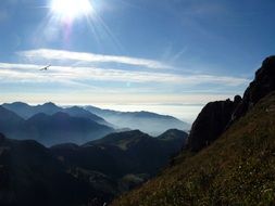 airplane flies over the peaks of the mountains against the summer sky