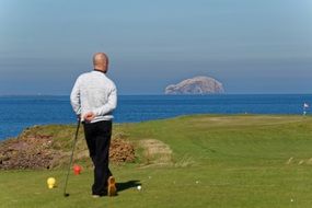 golfer standing on green field sea view