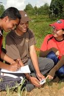 asian agriculture students measuring temperature of soil on field