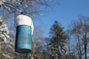 blue can with snow on a tree