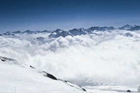 ski path on snowy alpine mountains above clouds