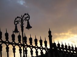 Metal fences with street lamps on a sunset background