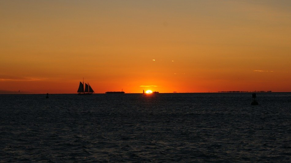 Beautiful and colorful sunset on horizon of water with the ship