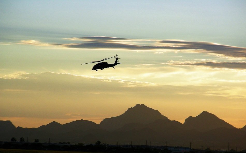 Military helicopter is flying over the mountains