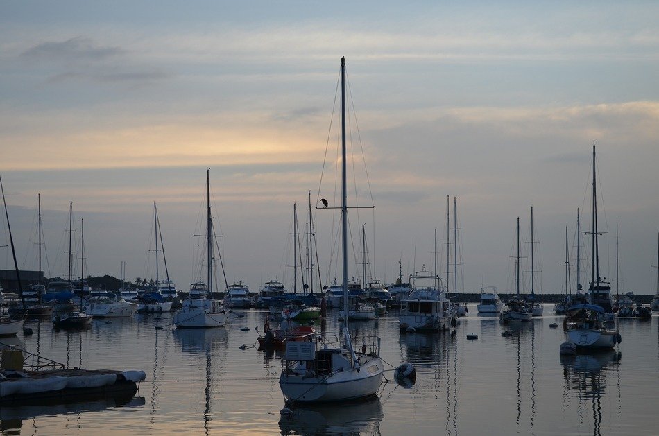 sunset behind the clouds amid boats in the ocean