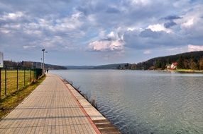 Beautiful walking path by the lake near the shore with green trees