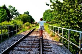 girl goes on rails on a summer day