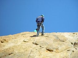 man climbing mountain by rope