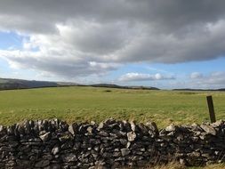 wall of stones near the green field