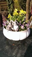 ceramic rabbits in a flower bed with daffodils