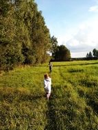 child walking on the green grass near the forest