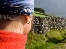 side view of a girl with piercings among colorful plants under cloudy sky in nature