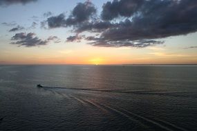 Top view of a boat on the ocean at beautiful and colorful sunset on horizon