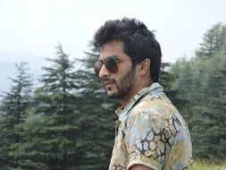 a young man in sunglasses on green landscape with the plants