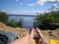 lying man feets on beach sand