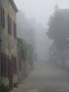 autumn fog in alley of old city, france, brittany